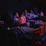 Smiling group holding CKSC banners and popcorn in the cinema hall