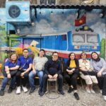 Group resting at colorful mural wall during Vietnam tour